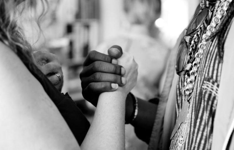 Cultural Diversity - grayscale photo of man and woman holding their hands