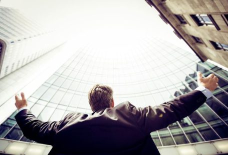 Success Measure - low-angle photography of man in the middle of buidligns