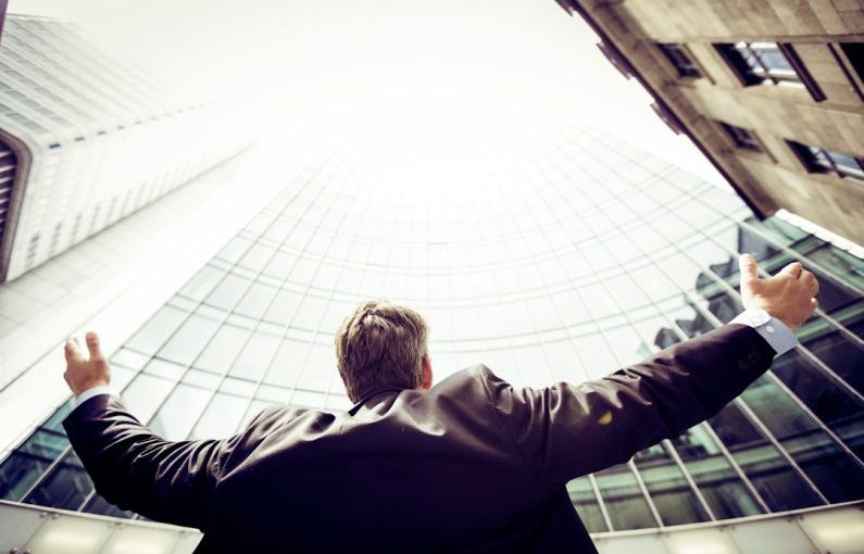 Success Measure - low-angle photography of man in the middle of buidligns