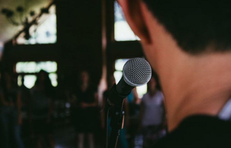 Public Speaking - man standing in front of microphone