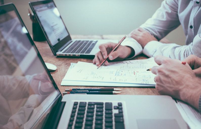 Budget Planning - person holding pencil near laptop computer