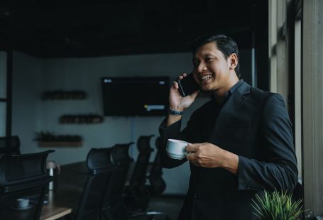 Success Measurement - smiling man holding cup and using smartphone