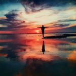 Life Change - silhouette of person standing on rock surrounded by body of water