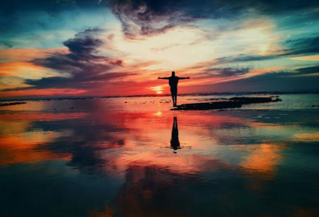 Life Change - silhouette of person standing on rock surrounded by body of water