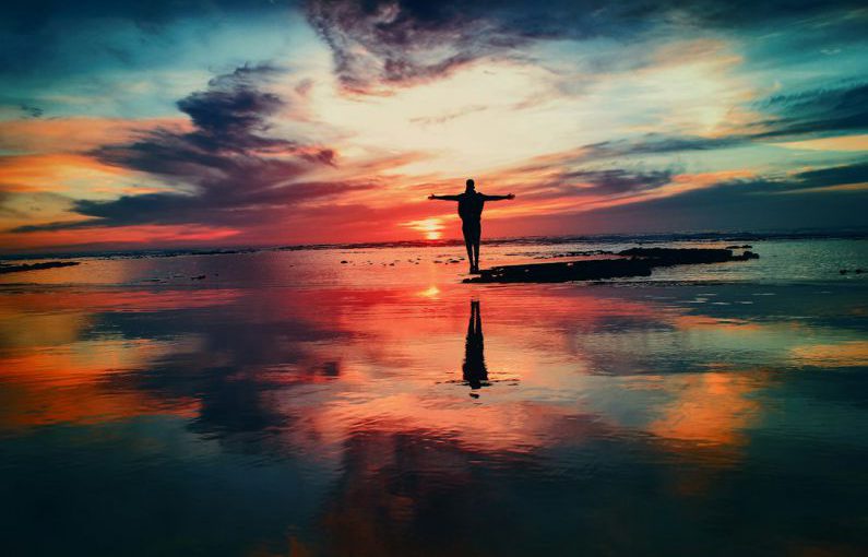 Life Change - silhouette of person standing on rock surrounded by body of water