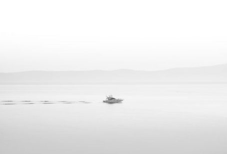 Arts Culture - a small boat floating on top of a large body of water