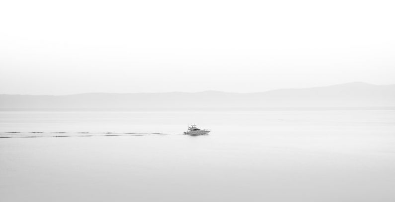 Arts Culture - a small boat floating on top of a large body of water