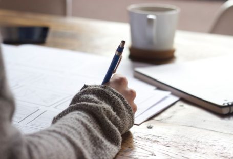 Personal Story - person writing on brown wooden table near white ceramic mug